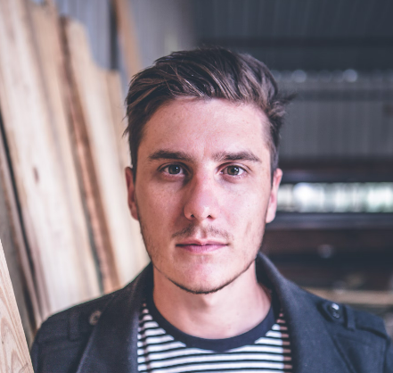 Man with short hair wearing a striped shirt and jacket, indoors